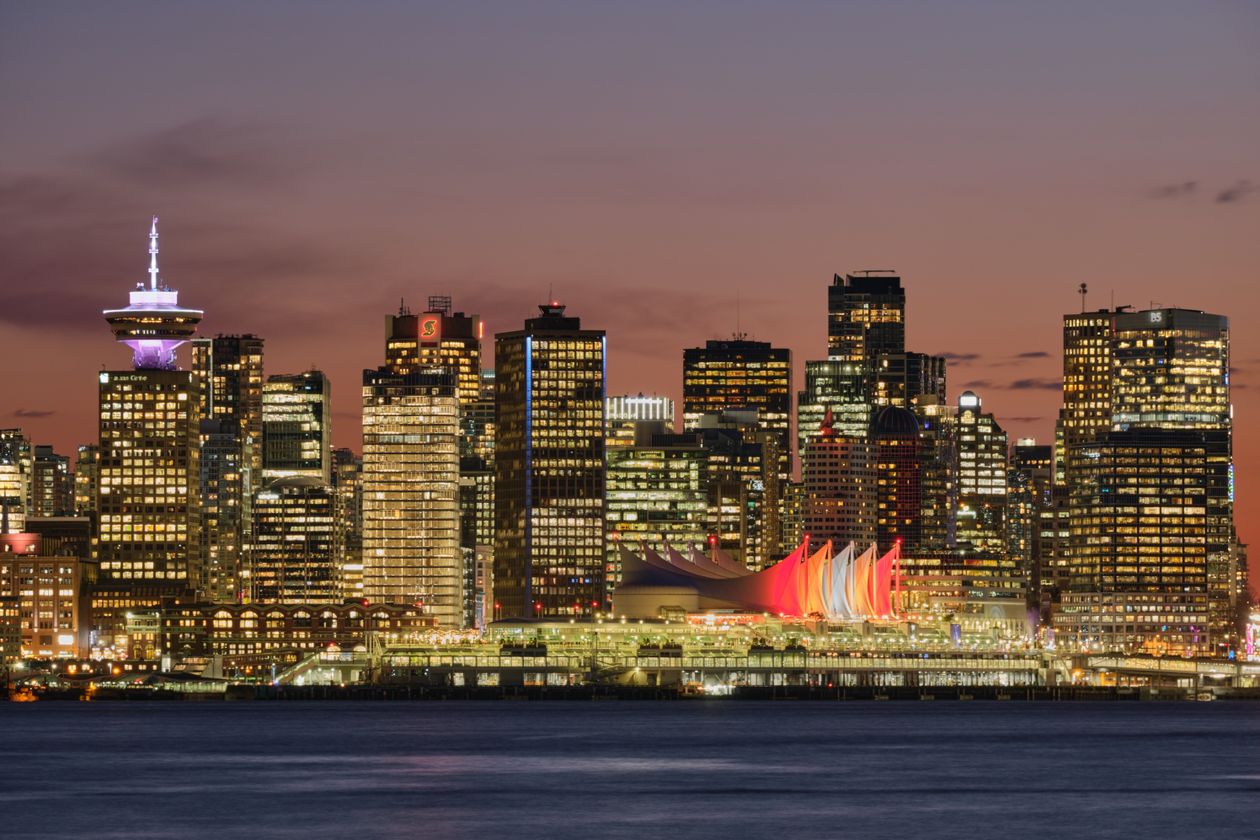 Downtown Vancouver skyline at dusk with illuminated condo towers over the harbour
