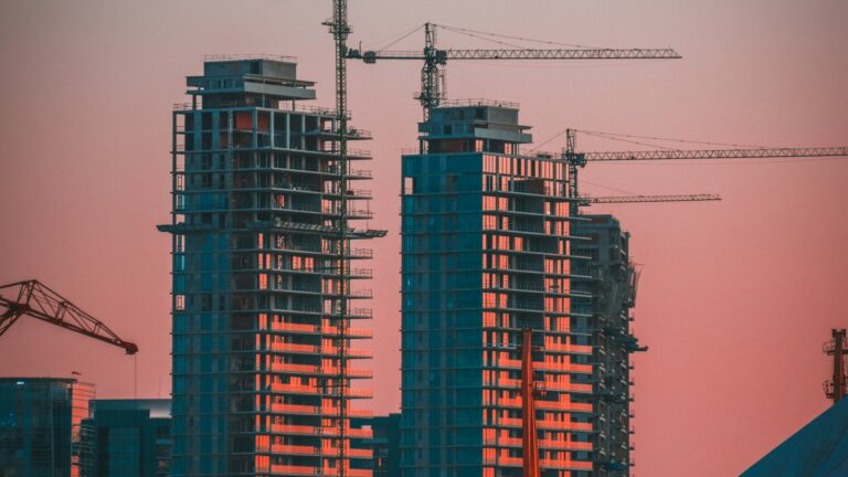 Concrete condo towers under construction with tower cranes at dusk, illustrating the multi-year Metro Vancouver presale completion timeline