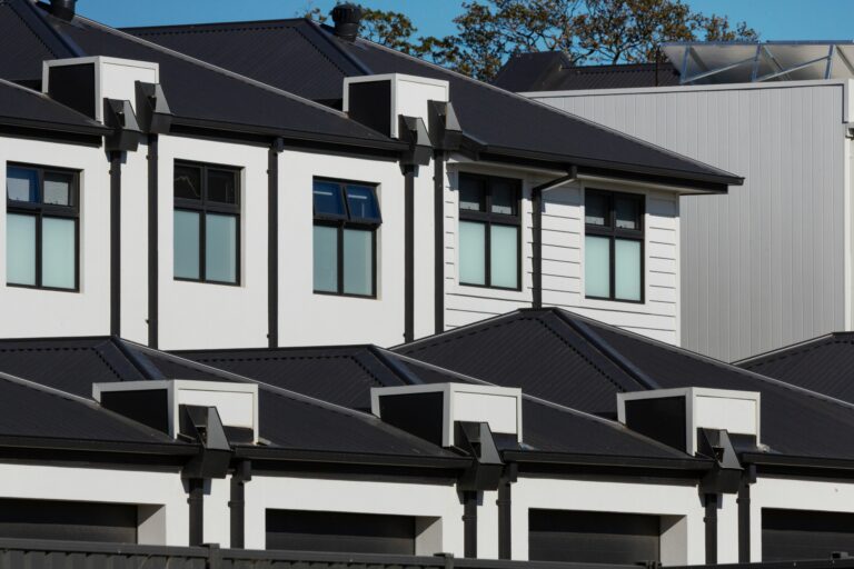 A row of newly built white townhomes with black roofs