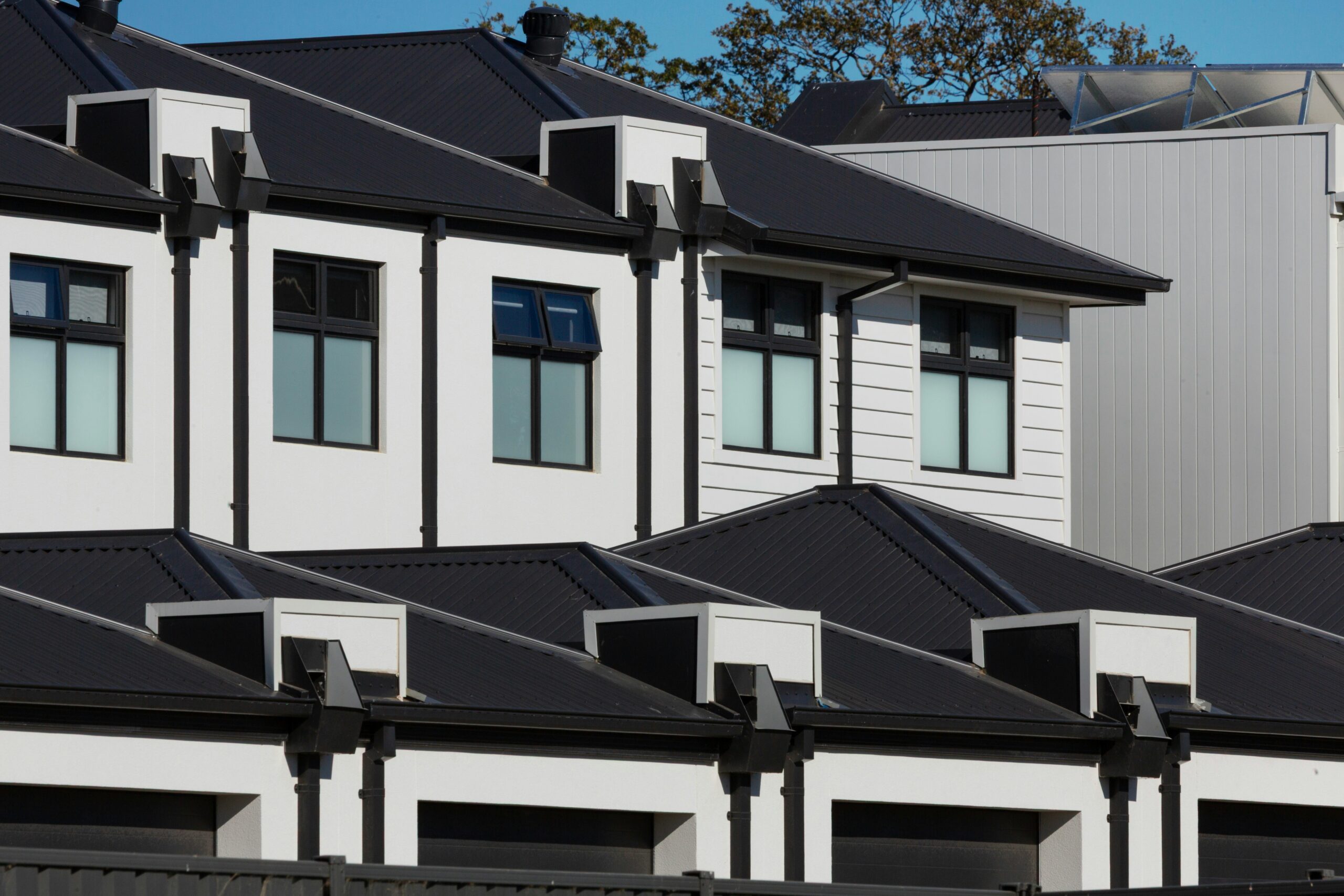 A row of newly built white townhomes with black roofs